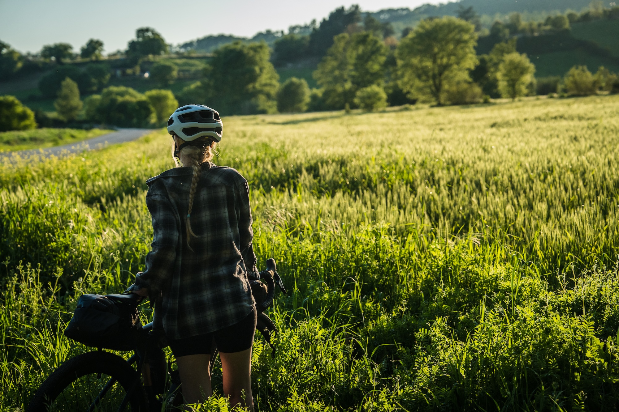 Villaggio Orizzonte — cyclist pausing in a sunlit green field